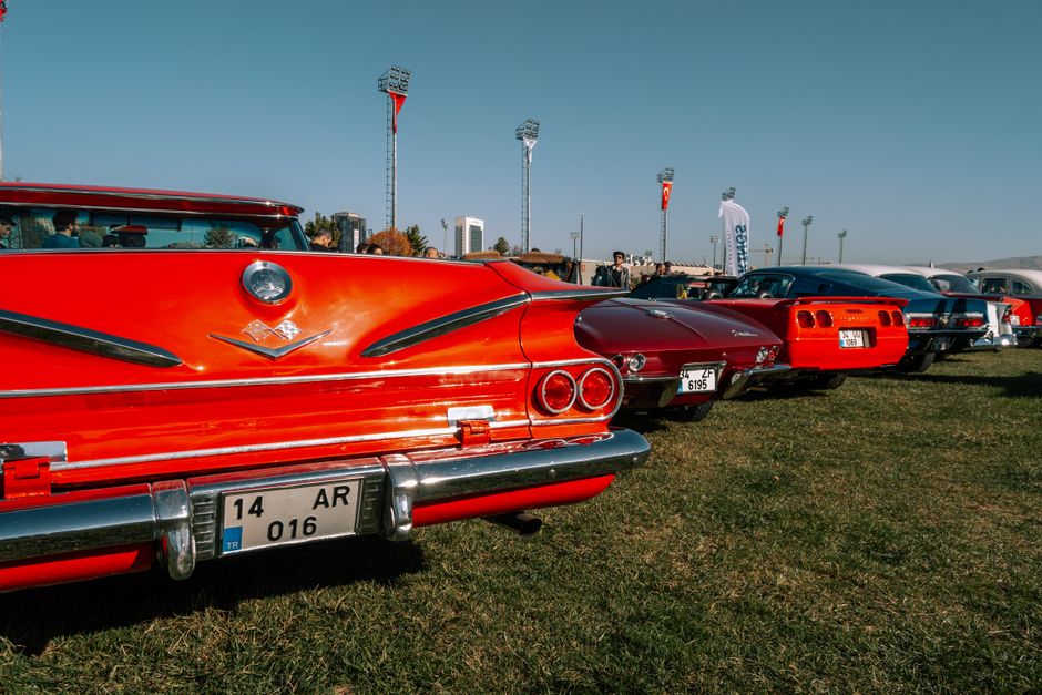Vintage cars lined up during an outdoor automotive show under clear skies.