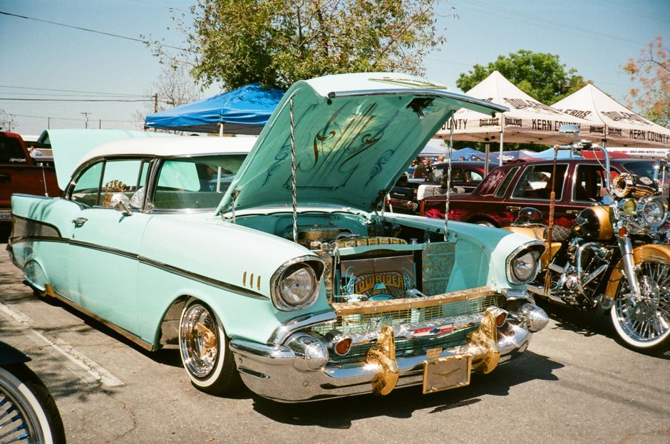 Vintage Chevrolet Bel Air with open hood on display at outdoor car exhibition.